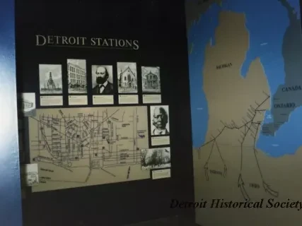 Display of historical maps and photos at a museum exhibit titled "Detroit Stations."