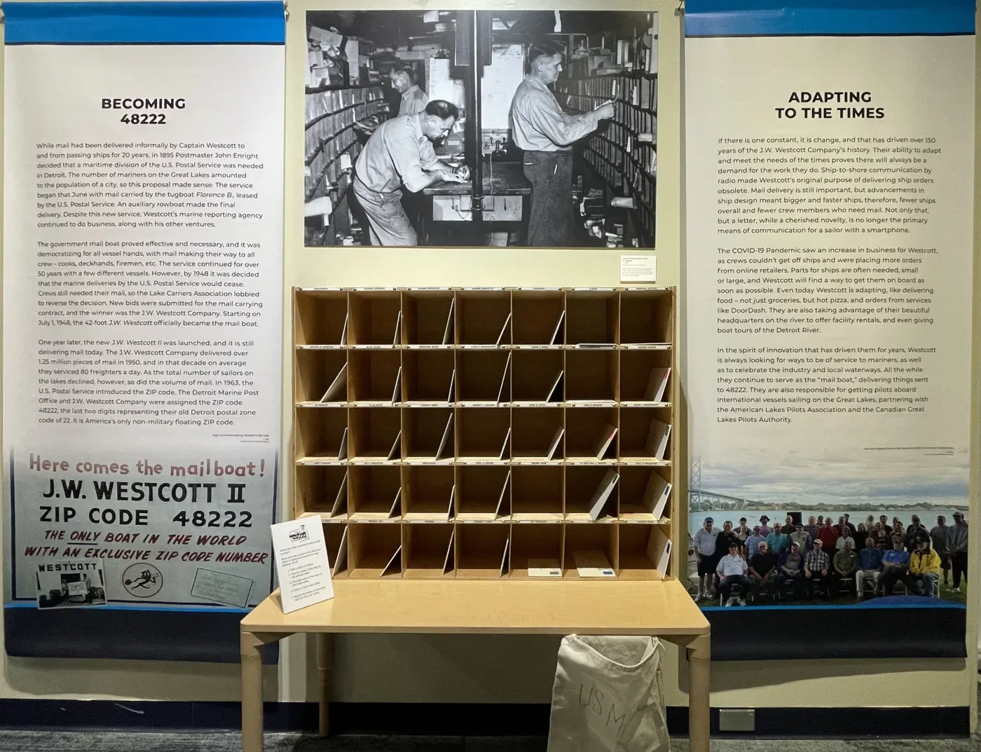 Mailroom exhibit with vintage black-and-white photo above a wooden sorting table, flanked by informative display panels.