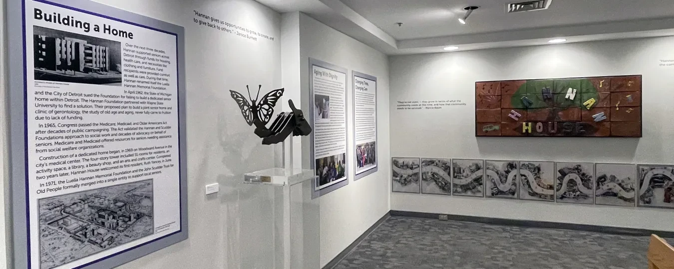 Museum gallery with informational panels, a sculpture, and a colorful mural on the wall.