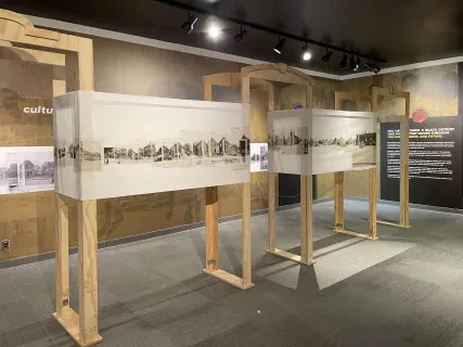 Exhibit room with historical panoramic photos on wooden frames, neutral tones.