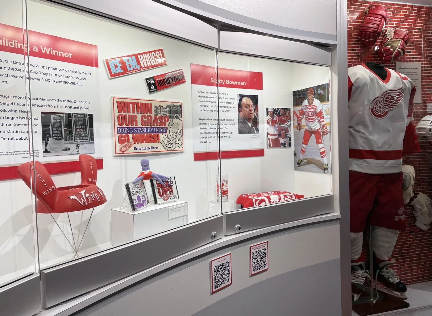 Exhibit display with hockey memorabilia, including a red and white uniform, and informational panels in a museum setting.